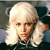 Pixelated portrait of a person with long white hair and a dark suit against a blurred background.