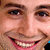 Pixelated close-up of a smiling person's face showing eyes, nose, mouth, and partial cheek with visible teeth and pink lips.