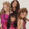 Four women in pink and magenta outfits pose together against a light background, smiling and interacting closely.
