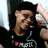 Pixelated static image of a person with dark hair wearing a black shirt, holding a white object near their face.