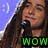 A pixelated image of a person with long brown hair holding a microphone, featuring green text reading "WOW" and a smiley face in the corner.