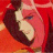 Pixelated close-up of a figure with dark hair and light skin against a red background, showing partial facial features and a blurred outline.