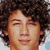 Static pixelated image of a person with dark curly hair, closed eyes, and light skin tone against a blurred background.