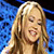 A pixelated contact sheet showing two frames of an animated icon featuring a blonde woman on the left and pink text reading "The REAL American Idol" on the right against a blue background.