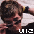 Pixelated image of a person with dark hair wearing a black shirt, holding a white object near their face, with text 'will<3' at the bottom right.