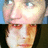 Pixelated close-up of a person's face with light skin, dark hair, and red lips against blue and black background.