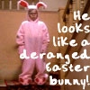 A person in a pink bunny costume with red accents stands against a brown background, overlaid with white pixelated text.