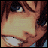 Pixelated anime-style face with brown hair and blue eyes, showing a smiling expression with visible teeth, accompanied by evolving text below the face.