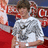 Pixelated image of a person in a white shirt with dark pattern, red and blue background elements, and visible pixelation artifacts.