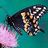 Pixelated image of a dark-colored insect with yellow markings on teal background, pink floral element visible.