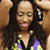 Static 50x50 pixel buddy icon showing a person with long dark hair wearing a low-cut top, holding an object near their face against a brown background.