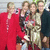 Four people in a group pose with one person in red, one in dark clothing, one in light clothing, and one in dark clothing, all standing close together.