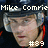 Pixelated image of a person wearing a dark helmet with light blue accents, featuring text above and below the face.