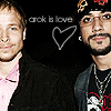 Two people stand side-by-side against a black background with 'crck is love' text and a heart outline above them.