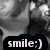 Black-and-white image of a person's face with a smiling expression, overlaid with a black banner containing the text 'smile:)' in white lowercase letters.
