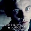 A close-up of a person with light hair and blue eyes, wearing a dark jacket with a light collar, against a dark background with text overlay.