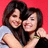Two women embrace against a red background; one wears light gray, the other black with green wristband.