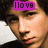 Pixelated image of a person with dark curly hair, wearing a dark top and pink scarf, overlaid with purple text boxes reading 'I love' and 'Nick Jonas'.