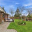 Pixelated landscape showing a house with dark roof, green grass, trees under blue sky with clouds.
