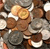 A pixelated image of a brown dog with white markings on its chest and face, positioned among scattered coins and a metallic object.