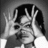 Black-and-white of four showing a child with dark hair making hand gestures and facial expressions, alternating between raised hands and open mouth