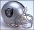 Static pixelated image of a silver football helmet with black and brown accents, featuring a shield-shaped logo on the side against a light gray background.