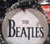 Pixelated static image of a circular white icon with bold black text reading "BEATLES" against a dark background, featuring visible dithering and low-resolution artifacts typical of early digital graphics.