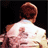 Pixelated image of a person with brown hair in a light-colored suit facing away from the viewer, next to a red square with white text.