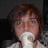 A pixelated image shows a person with brown hair holding a white object near their mouth against a dark background, next to green text reading "Domen the Starbucks Guy!".