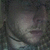 Pixelated grayscale image of a face with indistinct features, dark background, and no visible text or distinct objects.