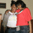 Two people embrace in a pixelated image; one wears a white shirt with light green and yellow patterns, the other a red top.
