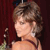 Static pixelated image of a woman with short brown hair in profile view against dark red background, wearing strapless dress and pearl earrings.