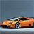 A static pixelated image of an orange sports car with black accents on a light blue background, viewed from a low angle showing the front and side. The car has a sleek design with visible headlights and wheels. The background is a solid light blue with subtle horizontal banding. The image has a low-resolution, blocky appearance typical of early digital graphics. The car's body is primarily orange with darker orange and brown tones. The wheels are dark with silver accents. The car's windows are dark, possibly black or dark blue. The image is cropped to show only the car and background, with no additional elements. The car is positioned slightly to the right of the center of the image. The image has a slightly blurred effect, possibly due to pixelation or compression. The car's headlights, a