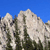 Pixelated static image of a mountain range with light gray peaks and dark green slopes under a solid blue sky.