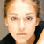 Static pixelated image of a person with light brown hair and fair skin wearing a dark top against a neutral background.