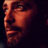 Pixelated static image of a person's face in profile view with warm orange and red tones against dark background.