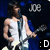 A pixelated image of a person in a white tank top holding a guitar, with text elements above and below.