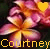 A pixelated flower with pink and orange petals, yellow center, and a heart symbol above it; the heart changes from yellow to red between frames.