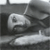A grayscale pixelated image of a stylized object with curved and angular shapes against a dark background.