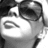 Pixelated grayscale image of a stylized face with dark hair, large eyes, and a small mouth, set against a light background.