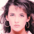 Static pixelated image of a person with dark curly hair, large black earrings, and light skin tone against white background.