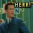 Pixelated image of a person in dark blue suit with light shirt and tie, hand raised to head, against green background with yellow text "HERR!".