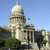 Pixelated image of a domed building with columns under a clear blue sky, green foliage in foreground.