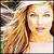 Pixelated close-up of a person with long light brown hair, fair skin, and closed eyes against a blurred background.