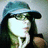 Pixelated static image of a figure with long dark hair wearing a teal cap, holding an object near the face against a light background.