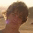 Static pixelated image of a person with short brown hair, visible ear, and light skin tone against a blurred background.