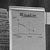 Static grayscale image of a rectangular frame with pixelated text and abstract shapes inside, bordered by darker vertical bars on both sides.