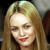 Pixelated close-up of a person with long light brown hair, fair skin, and red lips, set against a dark background with indistinct shapes.