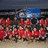 Group of people in red shirts on a beach with blue sky background and text "United 2nd place" on dark red