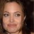 Pixelated close-up of a person's face with light skin tone, brown hair, and pink lips against a dark background.